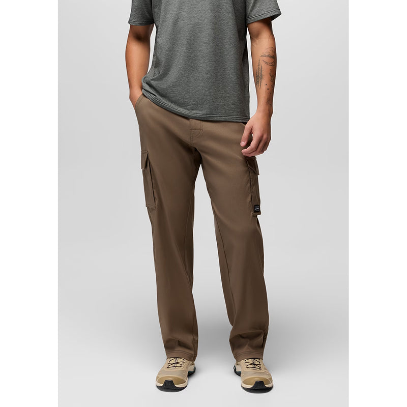 A model wearing brown cargo pants, a dark gray t-shirt, and beige sneakers, standing against a light gray studio background.