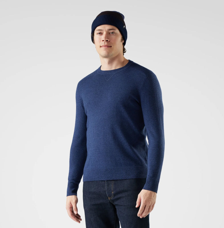 Man wearing a navy blue sweater and beanie on a light gray background