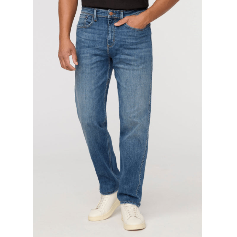 A person wearing medium-wash blue jeans with a straight-leg fit, paired with white sneakers, shown from the waist down against a light gray studio background.