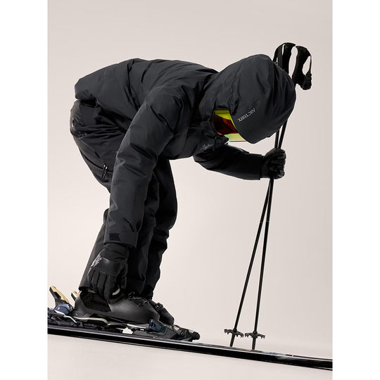 Person in black ski suit preparing to ski on a light gray background
