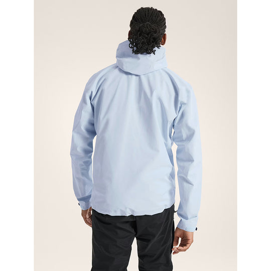 Person wearing a light blue jacket with a hood on a beige background