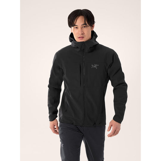 Person wearing a black jacket with a brand logo on a light gray background