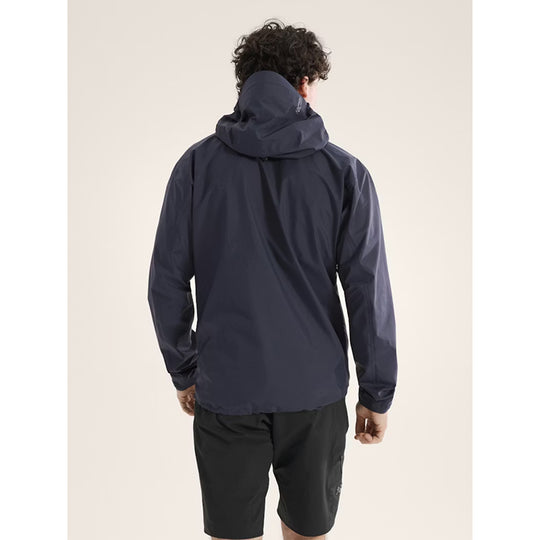 Person wearing a navy raincoat on a beige background