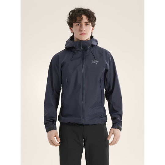 Person wearing a dark blue jacket with a brand logo on a beige background