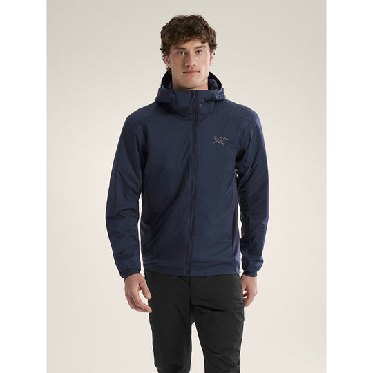 Man wearing a navy blue jacket with a brand logo on a beige background