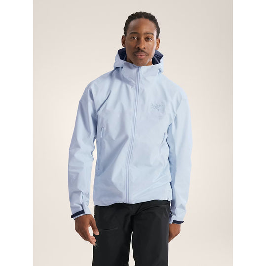 Man wearing a light blue jacket with a hood on a beige background