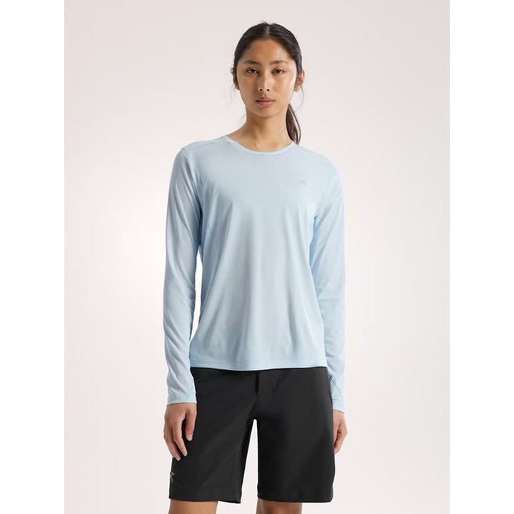 Person wearing a light blue long-sleeve shirt and black shorts on a white background