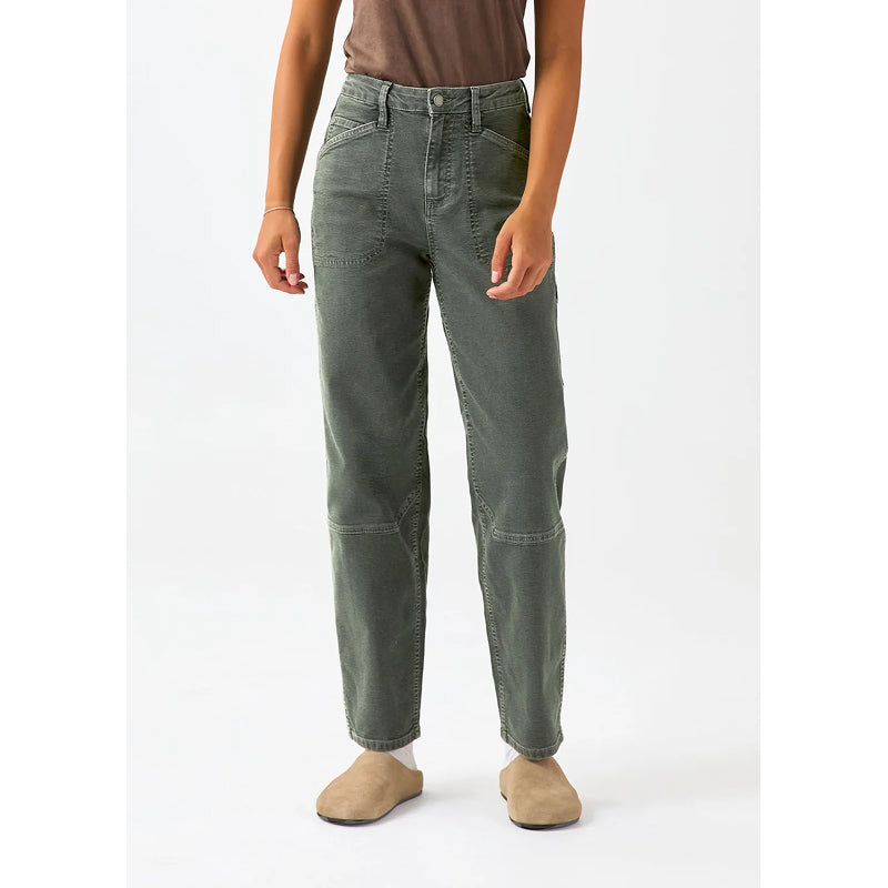 A model wearing a pair of dark olive green straight-leg jeans with contrast stitching and zippered knee pockets, paired with a brown top and beige slip-on shoes, against a plain white studio background.