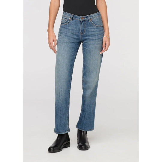 A model wearing a pair of medium-wash blue straight-leg jeans with black boots, shown from the waist down against a light gray studio background.