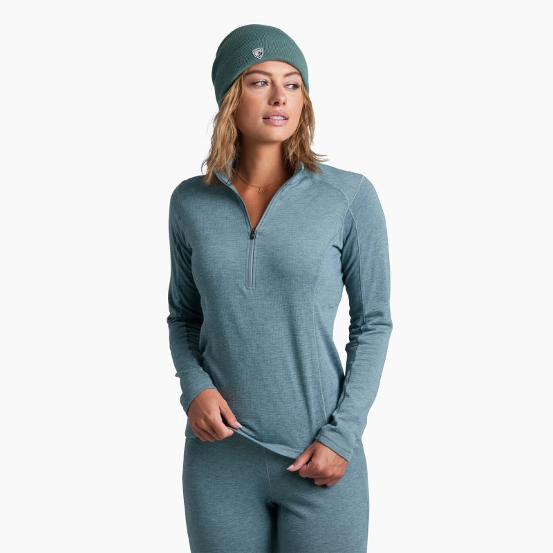Woman wearing a teal long-sleeve athletic top and leggings with a matching headband on a white background.