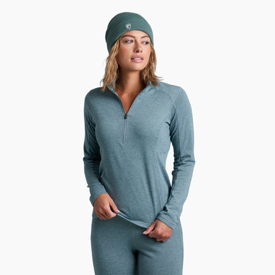 Woman wearing a teal long-sleeve athletic top and leggings with a matching headband on a white background.