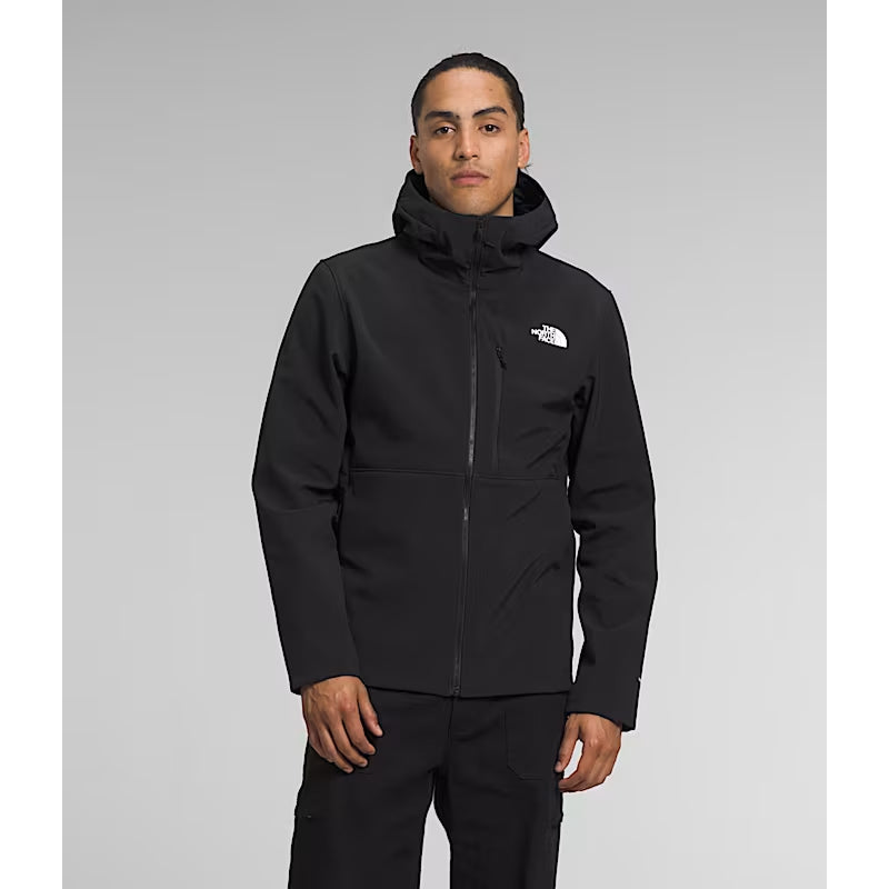 Person wearing a black jacket with a brand logo on a gray background