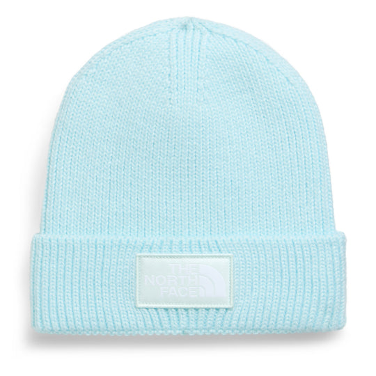 A light pastel blue knit beanie hat with a folded cuff and a white rectangular patch on the front that reads &
